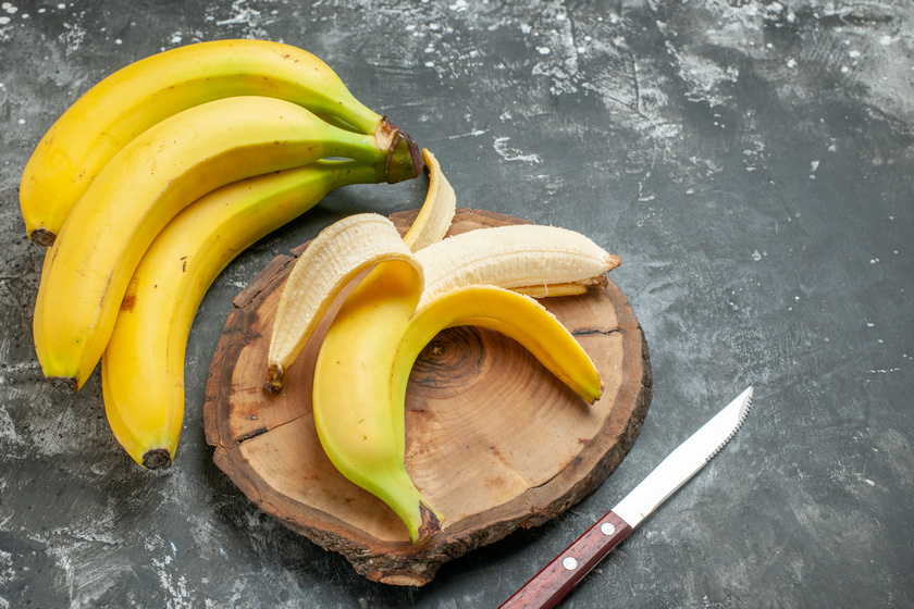 banane jedna oguljena na drvenoj dasci za sečenje nož pored